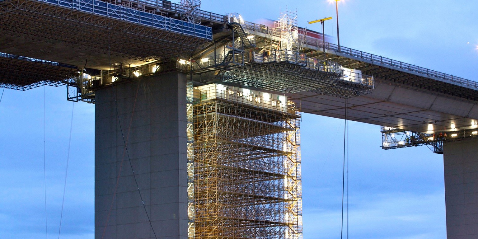 Industrial construction site with scaffolding and workers at height